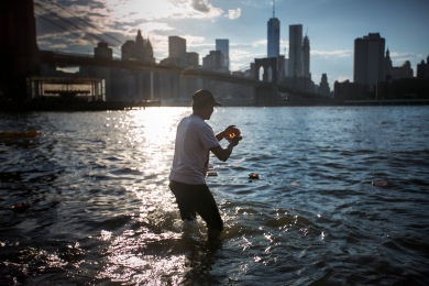 Ketan Patel, of Gujarat, India, places a candles in the East River during a Hindu Candle Lighting Ceremony in Brooklyn Bridge Park in Brooklyn, NY, on August 1, 2015.